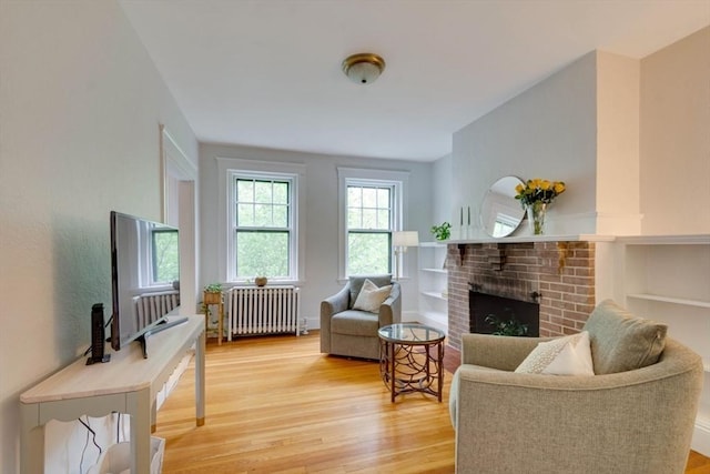 42 Linnaean St Unit 12, Cambridge, MA 02138 - living room with radiator, wood finished floors, a brick fireplace, and built in shelves