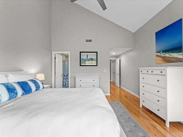 bedroom with baseboards, visible vents, high vaulted ceiling, light wood finished floors, and ceiling fan