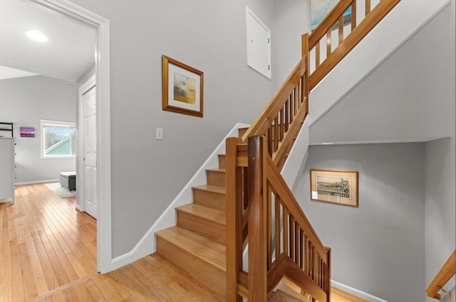 stairs with baseboards, a high ceiling, and hardwood / wood-style floors