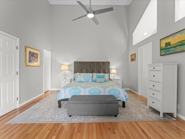 bedroom with a high ceiling, wood finished floors, and baseboards