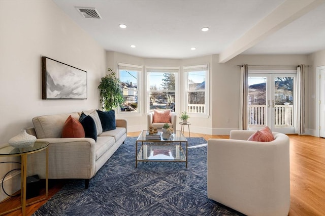 living room featuring hardwood / wood-style flooring, beamed ceiling, and a healthy amount of sunlight