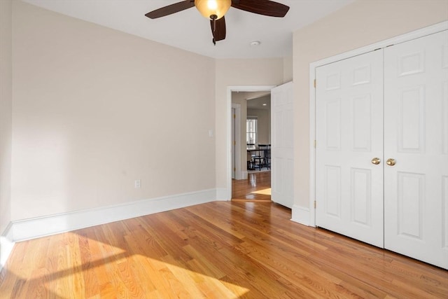 unfurnished bedroom featuring ceiling fan, a closet, and light wood-type flooring