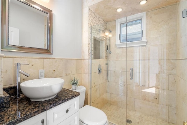 bathroom featuring toilet, vanity, tile walls, and an enclosed shower