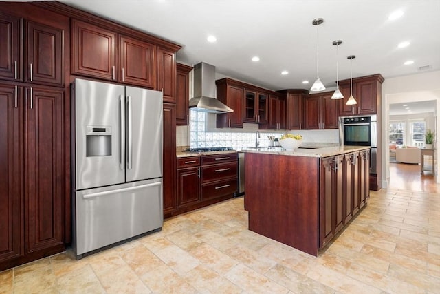 kitchen with tasteful backsplash, pendant lighting, light stone countertops, appliances with stainless steel finishes, and wall chimney exhaust hood