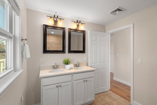 bathroom with tile patterned floors, vanity, and a healthy amount of sunlight