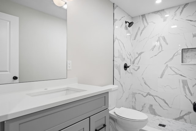 bathroom featuring tiled shower, vanity, and toilet