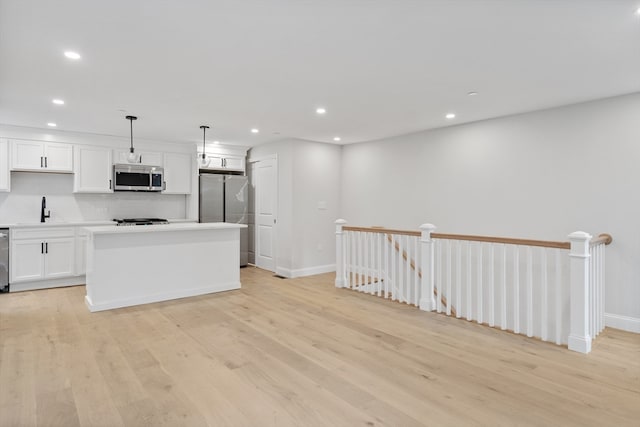 kitchen featuring decorative light fixtures, light hardwood / wood-style floors, sink, and stainless steel appliances