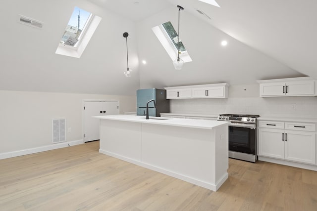 kitchen featuring hanging light fixtures, an island with sink, vaulted ceiling with skylight, white cabinets, and appliances with stainless steel finishes