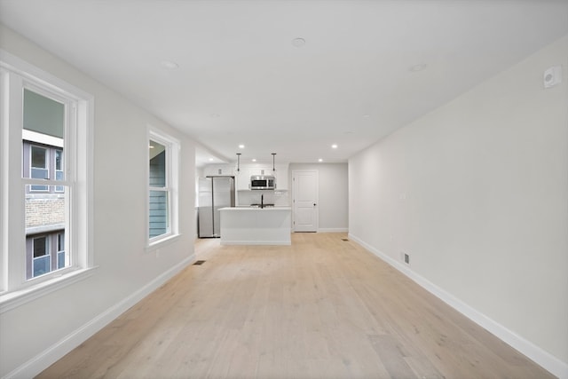 unfurnished living room with sink and light hardwood / wood-style flooring