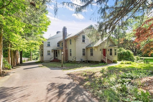 view of front of house featuring entry steps and a chimney