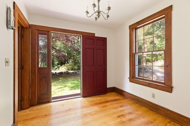 entrance foyer with a chandelier, light wood-type flooring, and baseboards