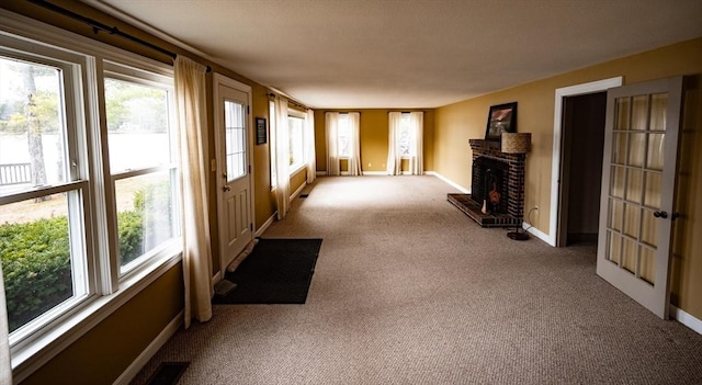 unfurnished living room featuring visible vents, carpet flooring, baseboards, and a brick fireplace