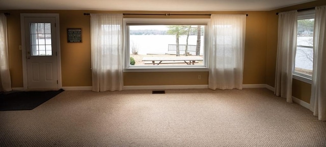 entryway featuring light carpet, a healthy amount of sunlight, baseboards, and visible vents