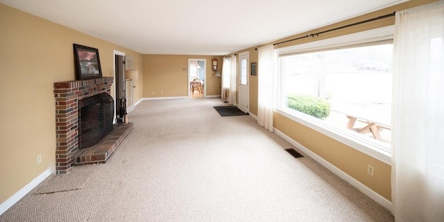unfurnished living room featuring a brick fireplace, visible vents, baseboards, and carpet floors