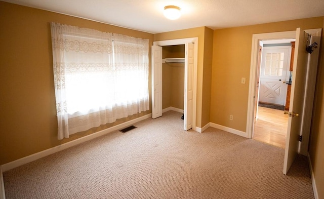unfurnished bedroom with a closet, light colored carpet, baseboards, and visible vents