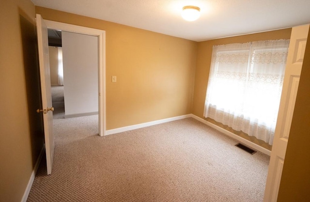 unfurnished room with carpet, visible vents, and baseboards