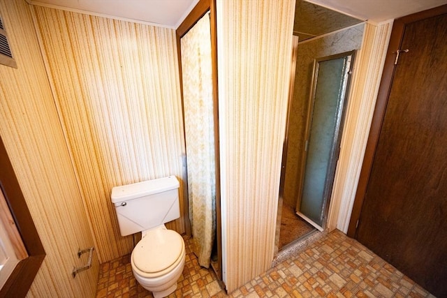full bath featuring a stall shower, wallpapered walls, and toilet