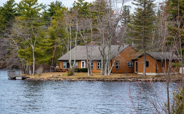 view of front of home with a water view, a dock, and faux log siding