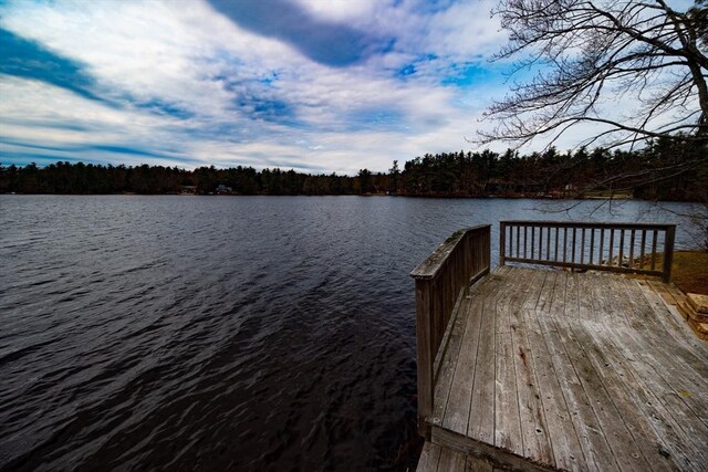 view of dock with a water view and a wooded view