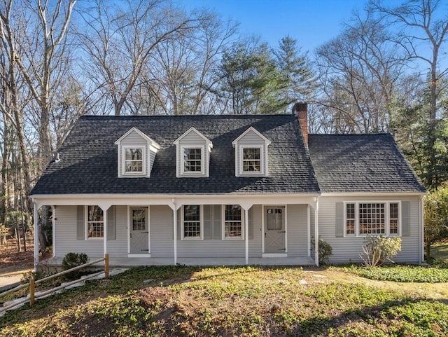 new england style home with covered porch and a chimney