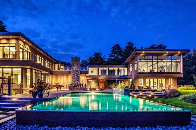 pool at night featuring a patio