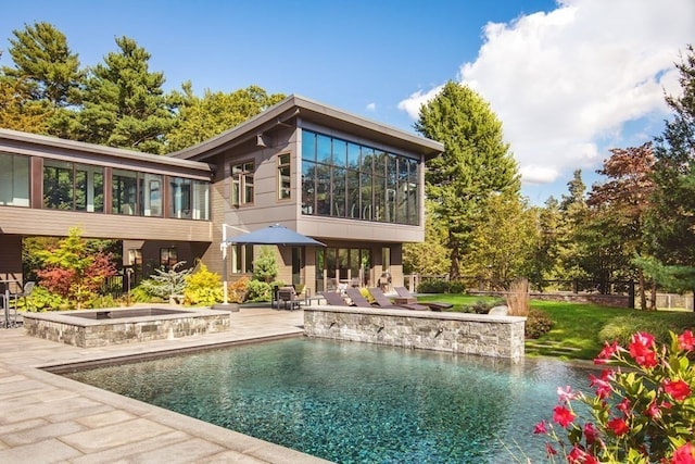 back of property featuring a patio area and a swimming pool with hot tub