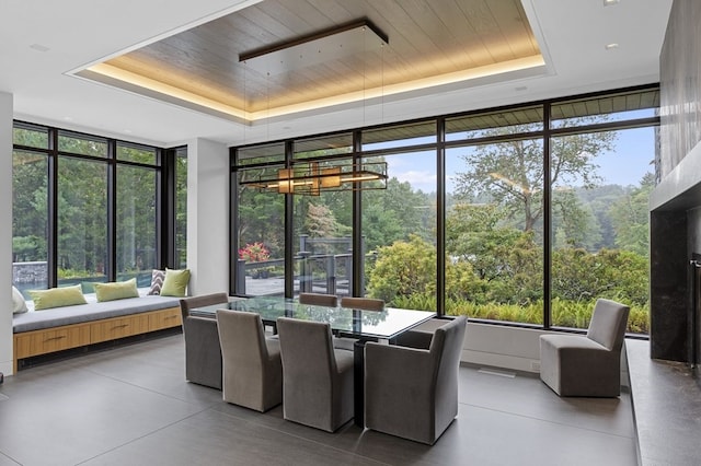 sunroom / solarium with a raised ceiling, wooden ceiling, and a wealth of natural light