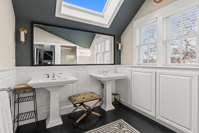 bathroom with sink, hardwood / wood-style flooring, and vaulted ceiling with skylight