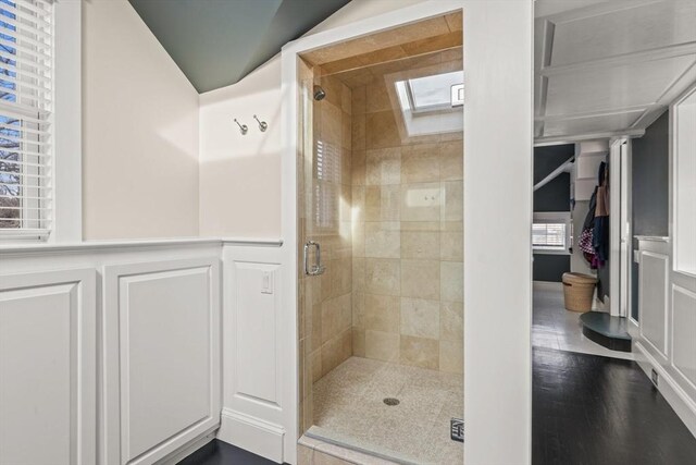 bathroom with an enclosed shower, a healthy amount of sunlight, a skylight, and hardwood / wood-style floors