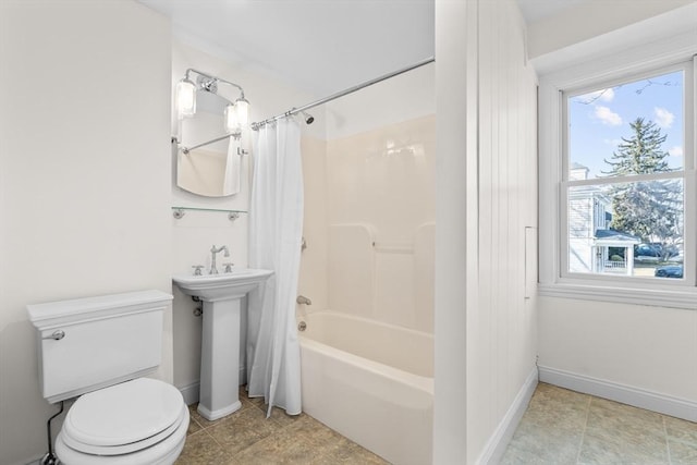 bathroom featuring shower / bath combination with curtain, toilet, baseboards, and a sink