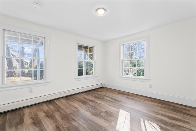 spare room with a wealth of natural light, baseboards, baseboard heating, and wood finished floors