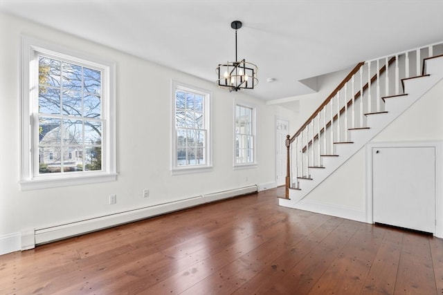 entrance foyer with baseboard heating, an inviting chandelier, stairs, and hardwood / wood-style flooring
