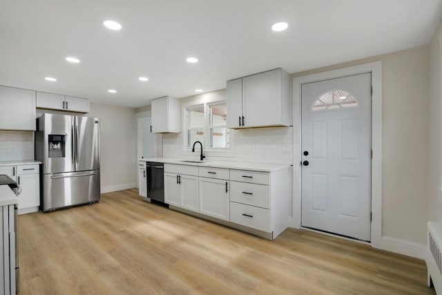 kitchen with sink, light hardwood / wood-style flooring, dishwasher, white cabinetry, and stainless steel refrigerator with ice dispenser