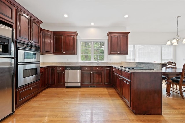 136 Howard St, Northborough, MA 01532 - kitchen featuring stainless steel appliances, a peninsula, a breakfast bar area, a chandelier, and light wood-style flooring