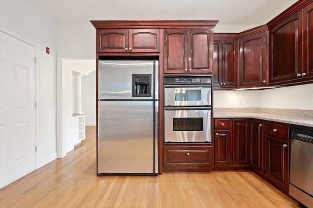 136 Howard St, Northborough, MA 01532 - kitchen featuring appliances with stainless steel finishes, light wood-style floors, light stone counters, and reddish brown cabinets