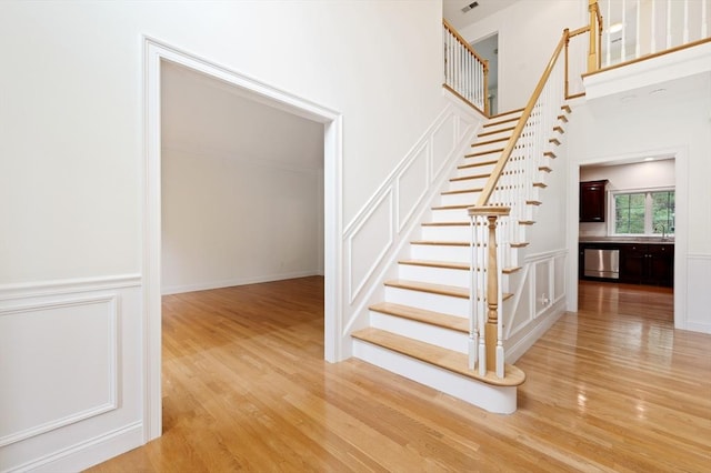 136 Howard St, Northborough, MA 01532 - stairway with a decorative wall, wood finished floors, a wainscoted wall, and a towering ceiling