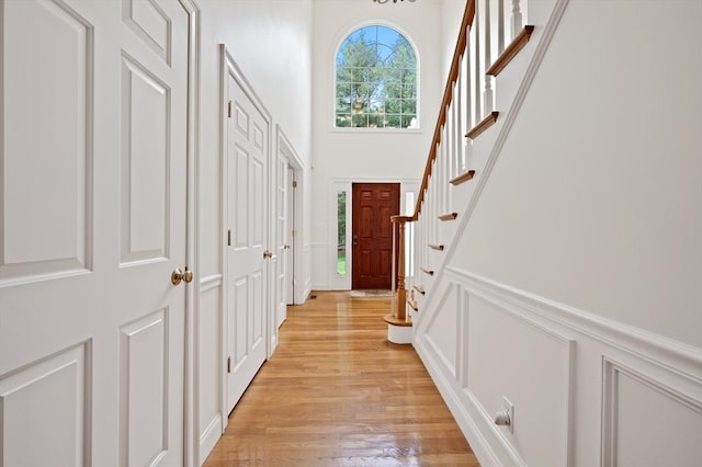 136 Howard St, Northborough, MA 01532 - doorway to outside with light wood-style floors, stairway, a high ceiling, and a decorative wall