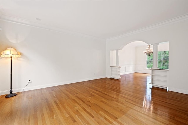 136 Howard St, Northborough, MA 01532 - spare room with arched walkways, ornamental molding, ornate columns, light wood finished floors, and a chandelier