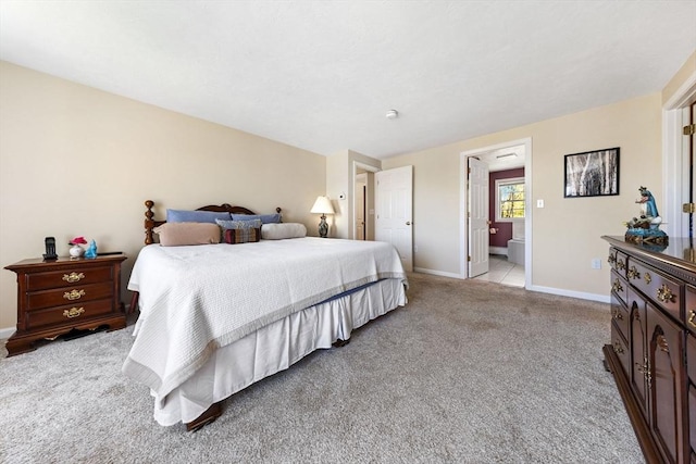 bedroom featuring baseboards, light colored carpet, and ensuite bathroom
