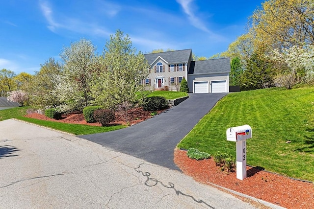 view of front of home featuring an attached garage, a front yard, and aphalt driveway