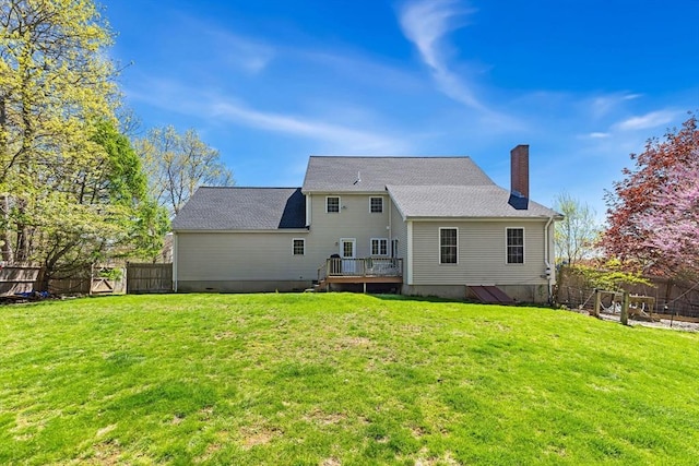 rear view of house with a fenced backyard, a chimney, a lawn, and a deck