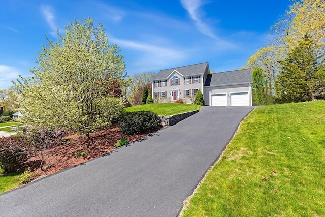 colonial-style house with a garage, driveway, and a front yard