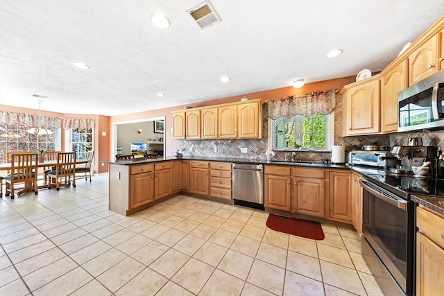 kitchen featuring visible vents, dark countertops, appliances with stainless steel finishes, tasteful backsplash, and a peninsula