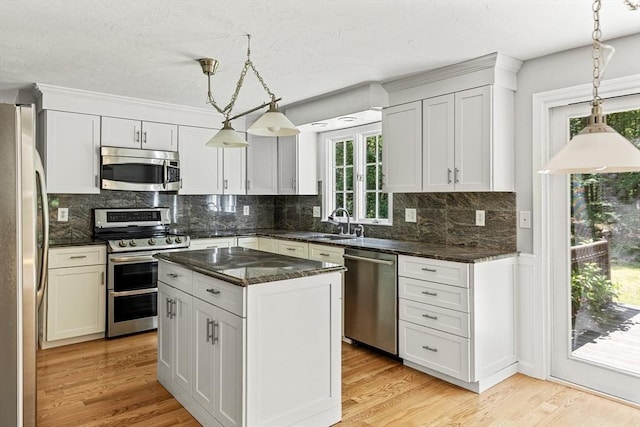 92 Clinton St, Hopkinton, MA 01748 - kitchen featuring stainless steel appliances, hanging light fixtures, decorative backsplash, a kitchen island, and light wood-style floors