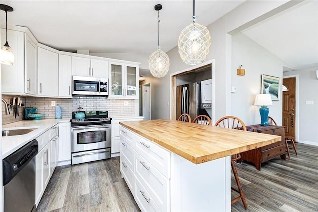 1 Shore Ave, Beverly, MA 01915 - kitchen featuring appliances with stainless steel finishes, a sink, a breakfast bar area, wood finished floors, and backsplash