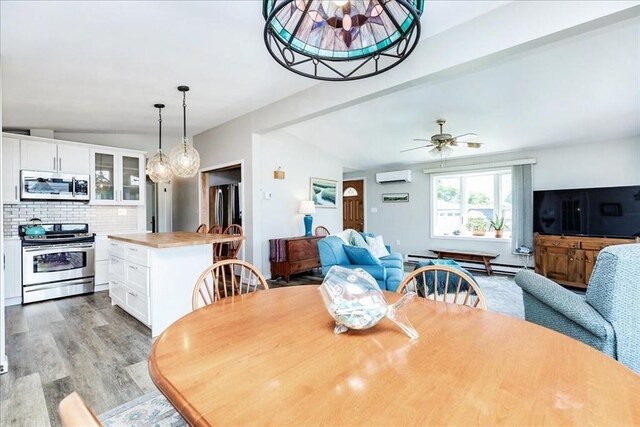 1 Shore Ave, Beverly, MA 01915 - dining space featuring a wall unit AC, light wood-style floors, ceiling fan, baseboard heating, and vaulted ceiling