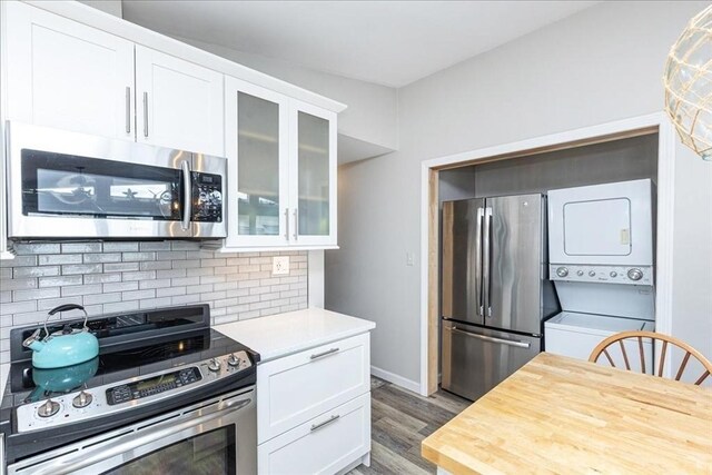 1 Shore Ave, Beverly, MA 01915 - kitchen with appliances with stainless steel finishes, estacked washer and dryer, white cabinetry, and decorative backsplash