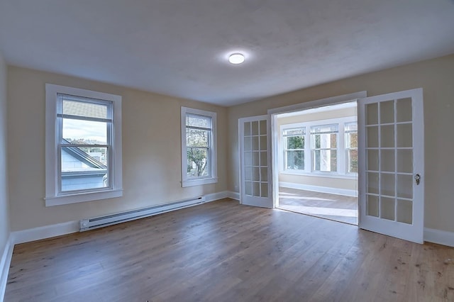 unfurnished room featuring baseboard heating, french doors, and hardwood / wood-style flooring