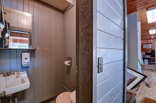 bathroom featuring wood walls, sink, and toilet