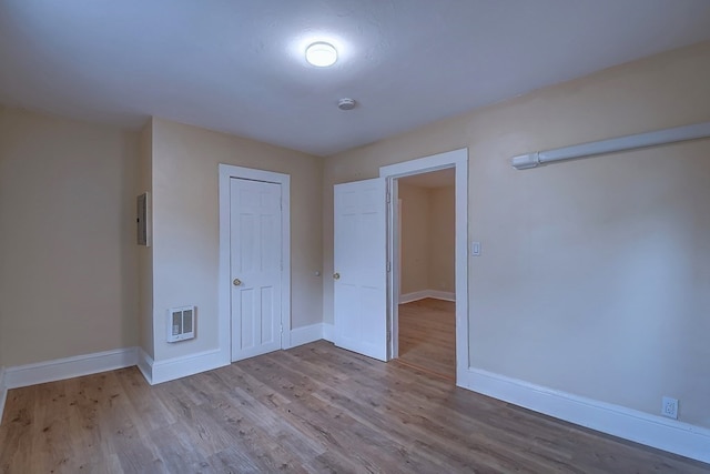 unfurnished bedroom with light wood-type flooring, electric panel, and a closet